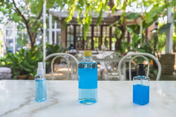 Close-up of 70% Blue Ethyl alcohol in different packages , spray bottle, plastic bottle and gel bottle, for coronavirus protection  on the marble table in the garden.