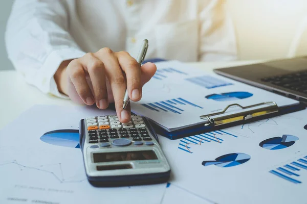 Hesap makinesi, grafik çizelgesi ve iş verilerini hesaplamak için çalışan iş adamı ya da muhasebecinin kalemini kapatın. Muhasebe belgeleri ve iş bilgileri ofisin masasında, iş konsepti.
