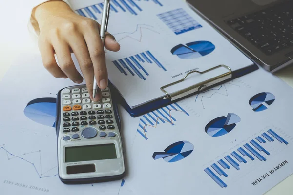 Grafik grafik kağıdındaki verileri hesaplamak için hesap makinesi kullanırken iş adamının kalemini kapat. Muhasebe belgeleri ve iş verileri iş yerindeki masanın üzerinde, iş konsepti.