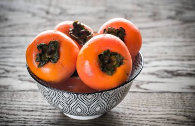 Bowl of fresh persimmons clipart