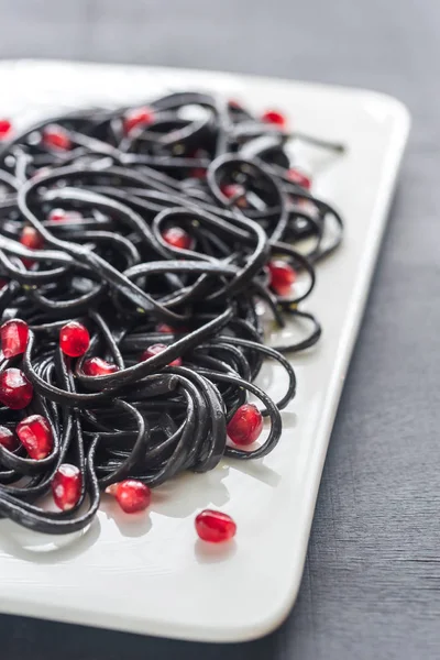 Black pasta with pomegranate seeds — Stock Photo, Image