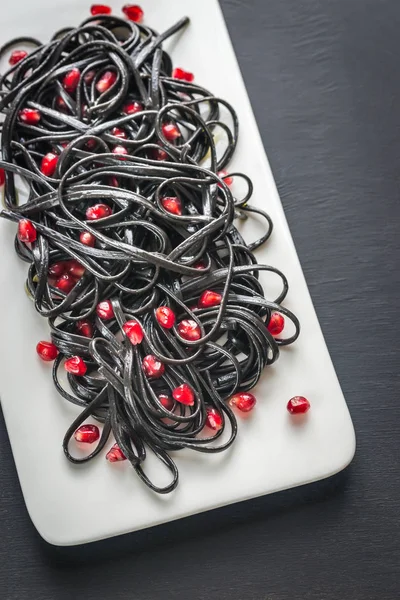 Black pasta with pomegranate seeds — Stock Photo, Image