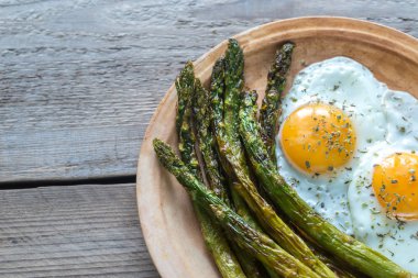 Plaka üzerinde kızarmış yumurta ile kavrulmuş kuşkonmaz