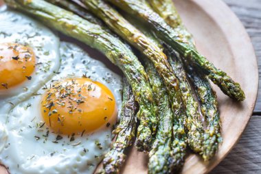 Plaka üzerinde kızarmış yumurta ile kavrulmuş kuşkonmaz
