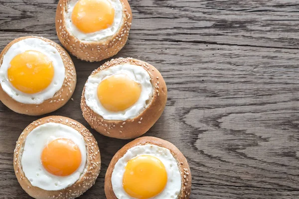 Egg-in-a-hole buns on the wooden board — Stock Photo, Image