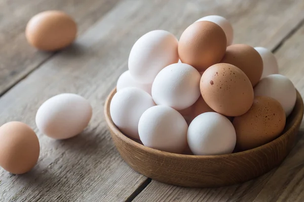 Wooden bowl of raw chicken eggs — Stock Photo, Image