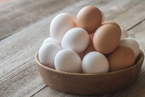 Wooden bowl of raw chicken eggs — Stock Photo, Image