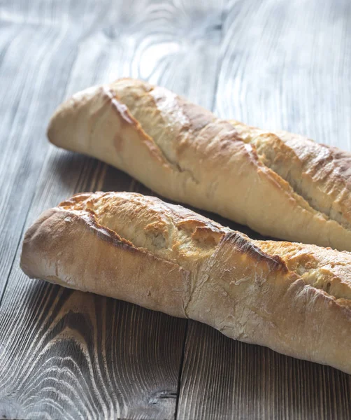 Due baguette sullo sfondo di legno — Foto Stock