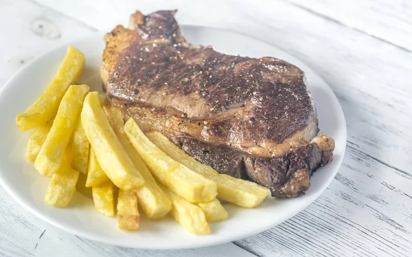 Bife de vaca com batatas fritas no prato — Fotografia de Stock