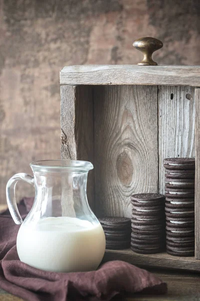 Biscoitos de chocolate com recheio cremoso com jarro de leite — Fotografia de Stock