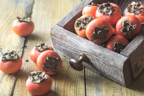 Wooden box of fresh persimmons — Stock Photo, Image