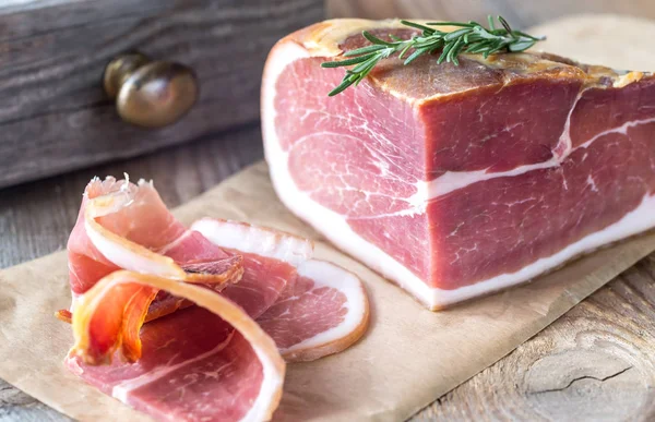 Prosciutto with fresh rosemary on the wooden board — Stock Photo, Image