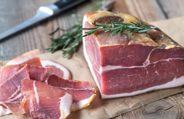 Prosciutto with fresh rosemary on the wooden board — Stock Photo, Image