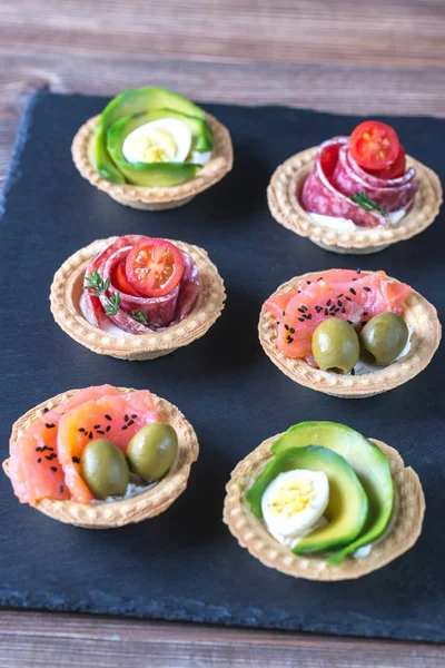 Tartelettes avec différentes garnitures sur la planche de pierre — Photo