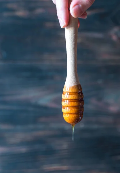 Pouring honey on the dark wooden background — Stock Photo, Image