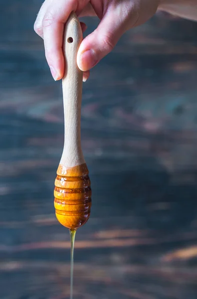 Despejando mel no fundo de madeira escura — Fotografia de Stock
