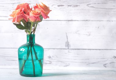 Ahşap arka plan üzerinde vazoda gül buketi