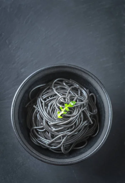 Bowl of pasta with squid ink with arugula leaf — Stock Photo, Image