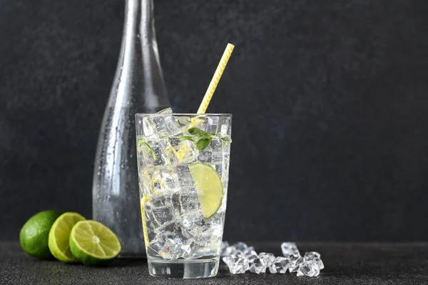 Glass of sparkling water with ice cubes and slice of lime — Stock Photo, Image