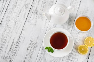 Ahşap zemin üzerinde bal ve limon olan bir fincan siyah çay.