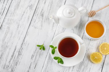 Ahşap zemin üzerinde bal ve limon olan bir fincan siyah çay.