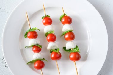 Caprese Salad skewers on white plate: top view