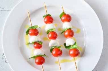 Caprese Salad skewers on white plate: top view