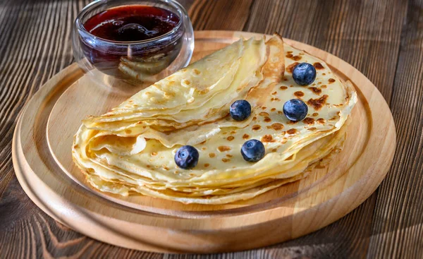 Crepes with fresh blueberries and berry syrup on wooden board