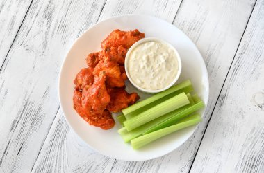 Bir kase tavuk kanadı ve ahşap arka planda mavi peynir sosu.