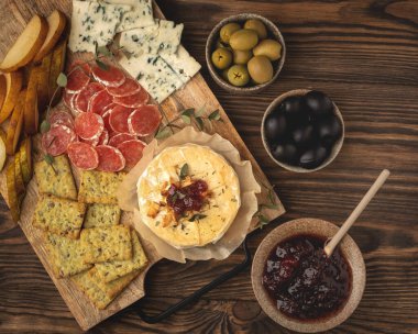 Ahşap bir tahtanın üzerinde, reçelli ve abur cuburlu peynirli fırında peynir.