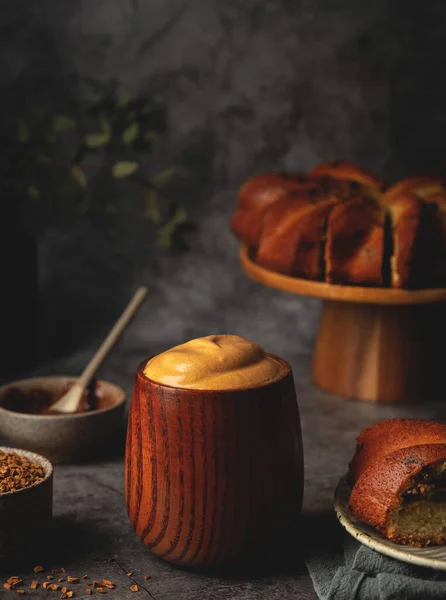 Dalgona kahvesi ahşap bir fincanda ve kek tezgahında. Yumuşak kremalı kahve. Eğilim Kore içeceği.