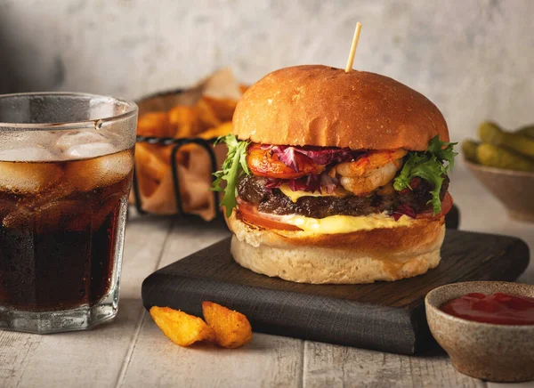 Karides ve sığır burger, bardak, kızarmış patates ve sosis. Yakın plan, hafif arkaplan.