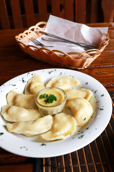 Rus vareniki patates püresi ve ekşi krema ve beyaz plaka üzerinde mantar sosu ile çanağı. Yakın çekim. — Stok fotoğraf