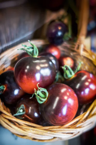 Korg med ekologiska bruna kumato tomater vid köket — Stockfoto