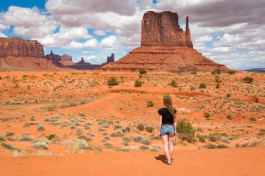 Anıt Vadisi 'nin ünlü kırmızı kayalarının yanında duran genç kadın. Navajo Kabile Parkı manzarası, Utah / Arizona, Usa
