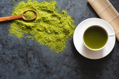 Beyaz bardakta yeşil çay. Düz yatıyordu. Koyu arkaplan