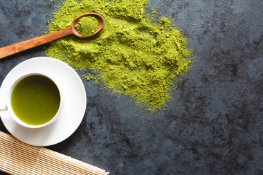 Beyaz bardakta yeşil çay. Düz yatıyordu. Koyu arkaplan