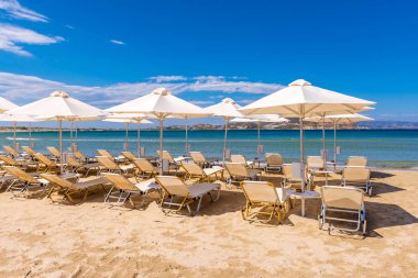 Agios Georgios sahilindeki güneş yatakları ve şempanzeler. Güzel altın kumu ve berrak suları olan çok popüler bir tatil yeri. Naxos Adası, Yunanistan.