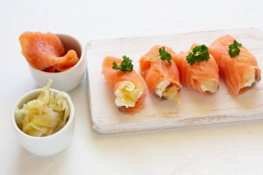 Süzme peynirle sarılmış füme somon dilimleri ve marine edilmiş zencefil. Parti atıştırması.