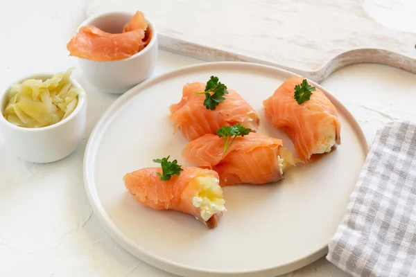 Slices of smoked salmon wrapped with cottage cheese and marinated ginger. Party snack.