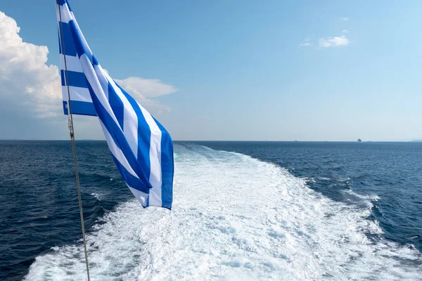 Ege Denizi 'nde bir feribotun arkasında köpüren Yunan bayrağı ve su izi. Yunanistan. — Stok fotoğraf