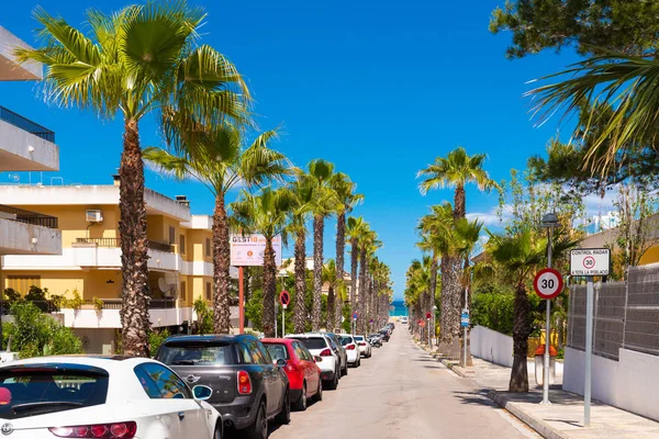 Can Picafort, Majorca - 2019. május 10.: Egy gyönyörű utca pálmafákkal, melyek a tengerhez vezetnek a Can Picafort-ban. Baleares, Spanyolország — Stock Fotó