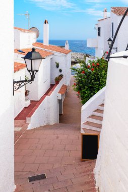 Binibeca Nou 'da geleneksel İspanyol mimarisi ve deniz manzaralı dar bir sokak. Menorca, İspanya