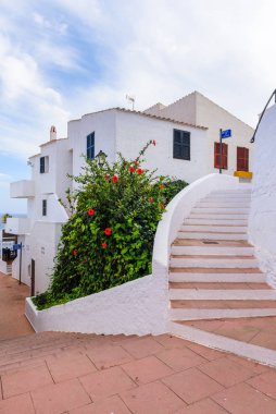 Menorca, İspanya - 14 Ekim 2019: Binibeca Nou köyünde çiçeklerle süslenmiş geleneksel İspanyol evlerinin merdivenleri. Menorka. İspanya