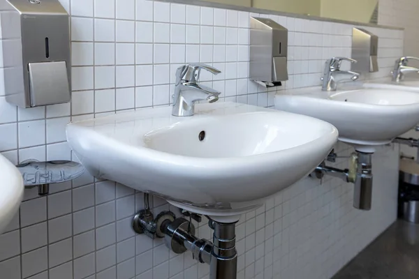 Row of white porcelain sink in public toilet. Antivirus health protection concept