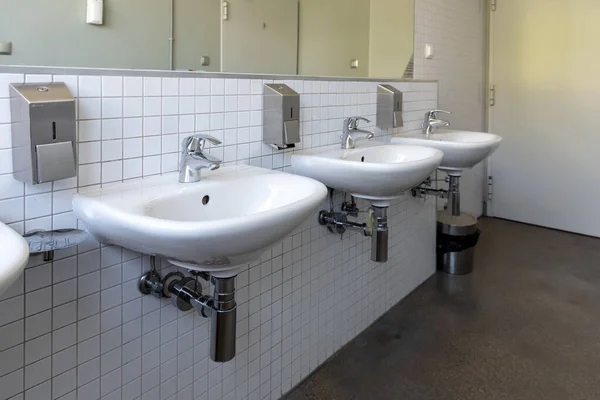 Row of white porcelain sink in public toilet. Antivirus health protection concept
