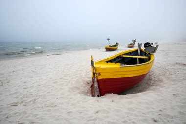 Bulutlu ve sisli bir günde sahilde balıkçı tekneleri. Baltık Denizi, Polonya