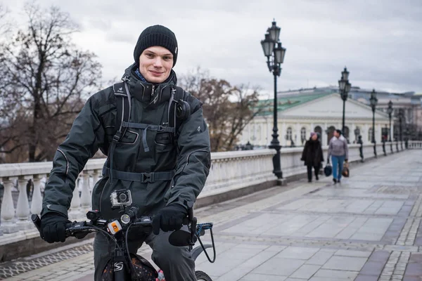 Mladý muž v teplé bundě a čepici na kole v centru Moskvy — Stock fotografie