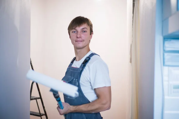 塗装修復作業用のローラーを持った若い男がアパートにされています。. ロイヤリティフリーのストック写真
