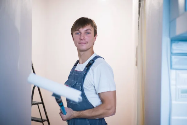 Joven con rodillo para trabajos de reparación de pintura ha estado en el apartamento . Fotos de stock libres de derechos